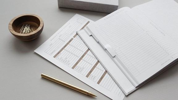 A blank journal and checklist spread out on a desk